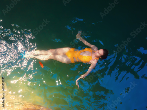 A girl swims in the turquoise water of a shady gorge shining in the sun