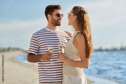 leisure  relationships and people concept - happy couple in sunglasses drinking champagne on summer beach