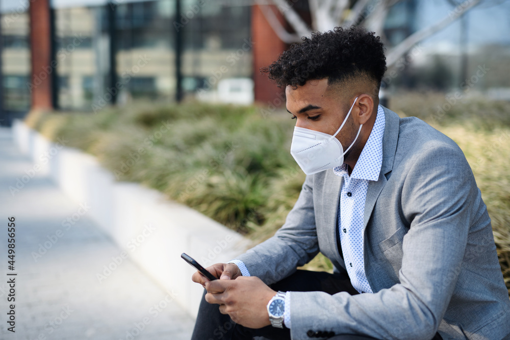Portrait of young man sitting outdoors in city, using smartphone. Coronavirus concept. Portrait of young man sitting outdoors in city, using smartphone. Coronavirus concept.