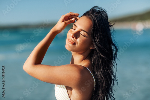 people, summer and swimwear concept - happy smiling young woman in bikini swimsuit on beach