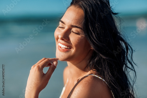 people, summer and swimwear concept - close up of happy smiling young woman on beach