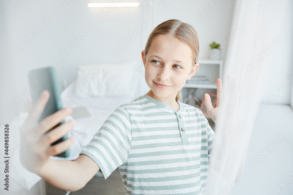 Waist up portrait of smiling girl video chatting via smartphone in hospital room, copy space Waist up portrait of smiling girl video chatting via smartphone in hospital room, copy space