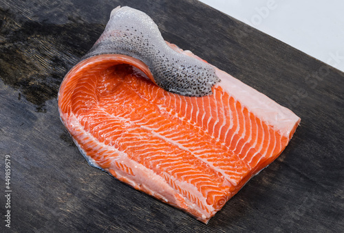 Raw trout fillet on the skin on a dark surface