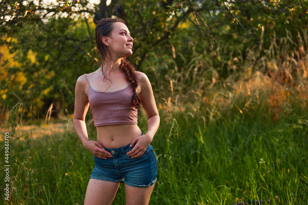 Beauty in nature woman enjoying the summer sun outdoors in the park or garden. Dressed jeans shorts and beige top in golden hour Beauty in nature woman enjoying the summer sun outdoors in the park or garden. Dressed jeans shorts and beige top in golden hour