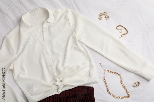 Stylish clothes and golden bijouterie on white fabric, flat lay © New Africa