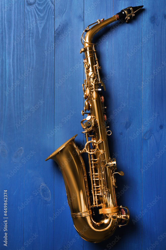 Naklejka premium Beautiful saxophone on blue wooden background, top view