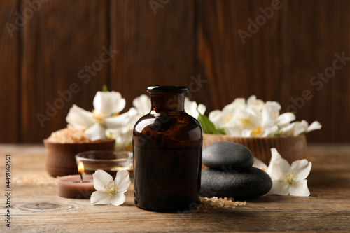 Beautiful composition with jasmine essential oil and fresh flowers on wooden table