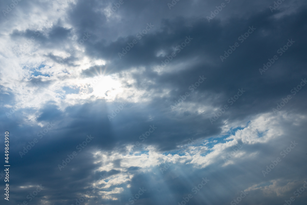Dramatic blue sky with clouds and sun rays.Summer Sun rays at sunset. Dramatic blue sky with clouds and sun rays.Summer Sun rays at sunset.