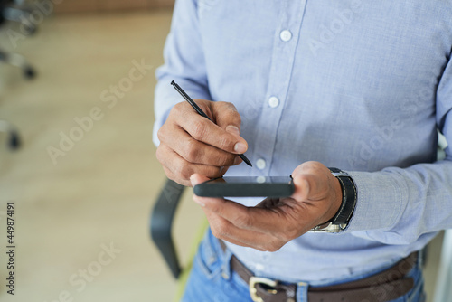 Hands of businessman using digital pen when working on smartphone