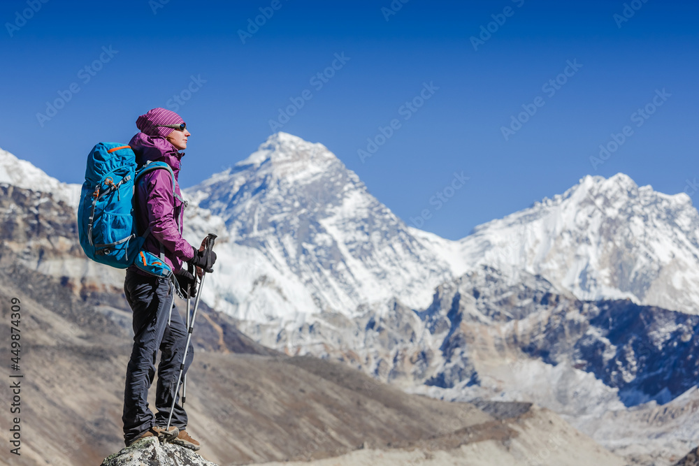Happy Woman Traveler with Backpack hiking in Mountains with Everest background. mountaineering sport lifestyle concept