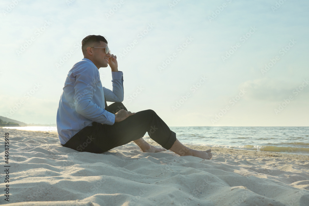 Happy businessman sitting on sandy beach. Business trip Happy businessman sitting on sandy beach. Business trip