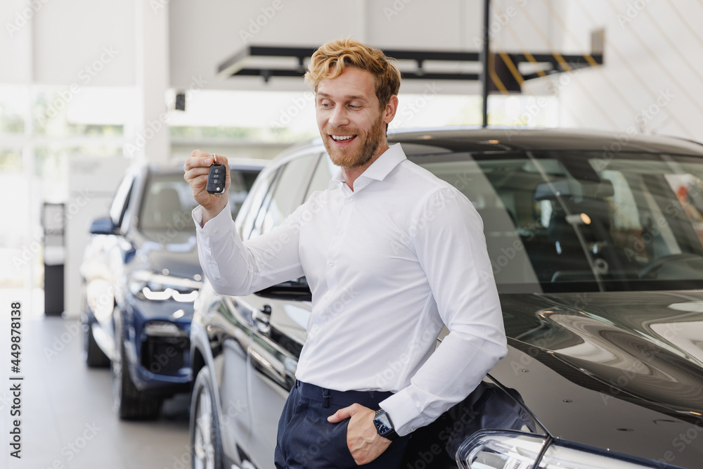 Man customer male buyer businessman client in white shirt hold keys fob chooses auto wants to buy new automobile in car showroom vehicle salon dealership store motor show indoor. Car sales concept Man customer male buyer businessman client in white shirt hold keys fob chooses auto wants to buy new automobile in car showroom vehicle salon dealership store motor show indoor. Car sales concept