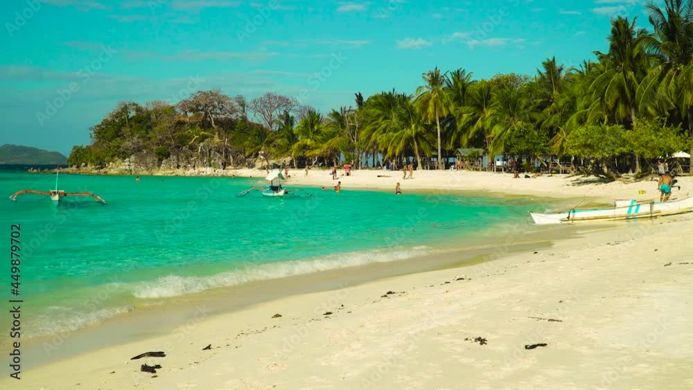 Tourists enjoy their vacation on a tropical beach with palm trees. Malcapuya, Philippines, Palawan. Tourists enjoy their vacation on a tropical beach with palm trees. Malcapuya, Philippines, Palawan.