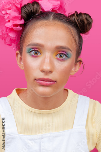 Latin teenager with makeup looking at you on pink background