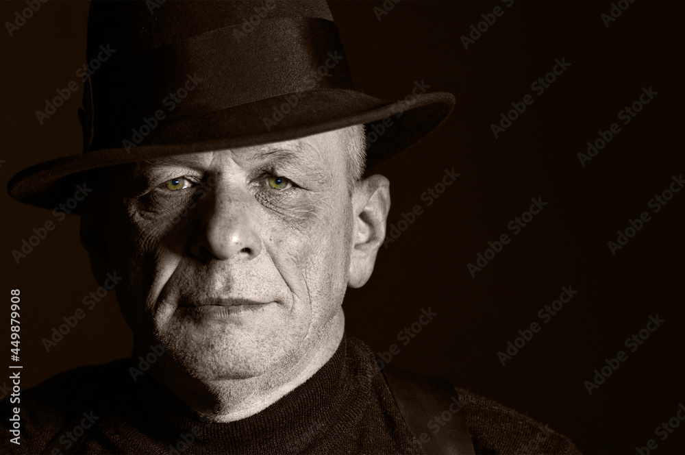 Portrait of a senior man with hat in a studio. Low key shot. Sepia toned