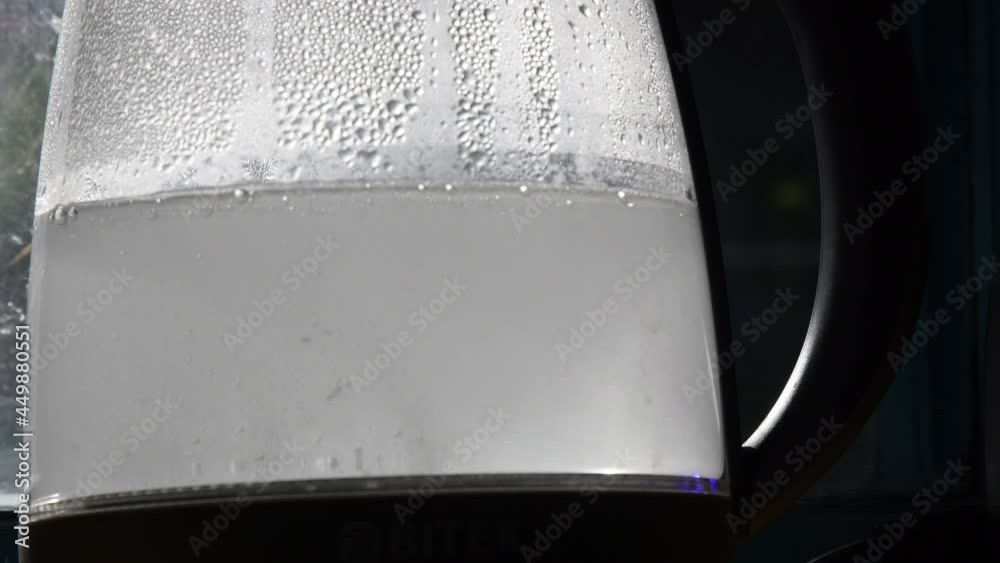 Water bubbles and scale pieces in hot water boiling inside teapot with blurry condensation on glass surface. Limescale in turbid water boiled in old transparent kettle in kitchen Water bubbles and scale pieces in hot water boiling inside teapot with blurry condensation on glass surface. Limescale in turbid water boiled in old transparent kettle in kitchen