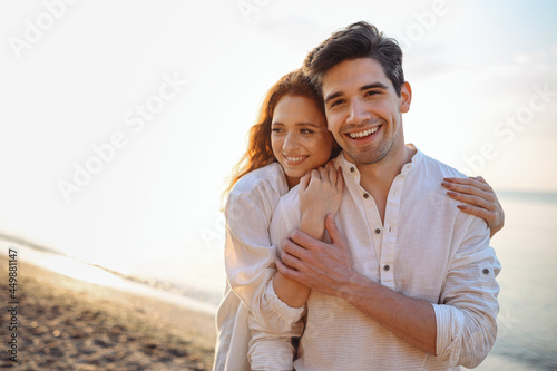 Romantic satisfied sunlit smiling happy young couple two friends family man woman in casual clothes hug each other at sunrise over sea beach ocean outdoor exotic seaside in summer day sunset evening.