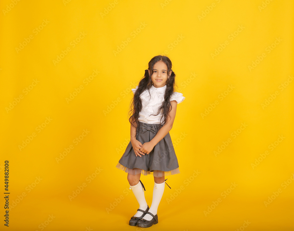 a beautiful happy dark-skinned schoolgirl girl with dark hair in a school uniform, a gray skirt and a white blouse