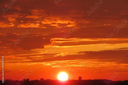 Orange fiery sunset over the city, the sun sets over the horizon © natalya2015