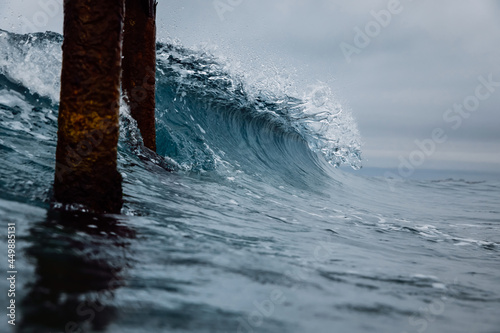 Fototapeta Naklejka Na Ścianę i Meble -  Crashing glassy wave on the beach. Breaking ocean wave and pier