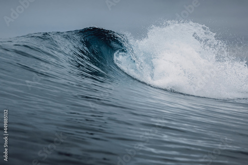 Crashing glassy wave on sandy beach. Perfect swell for surfing