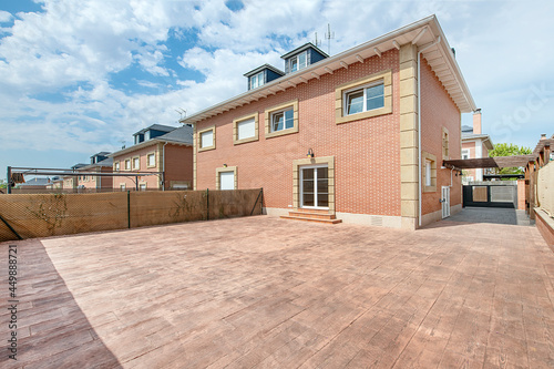 large patio tiled in wood ceramic simile of a single-family house on the outskirts of the city of Madrid, with slate ceilings and exposed brick facade with granite finishes