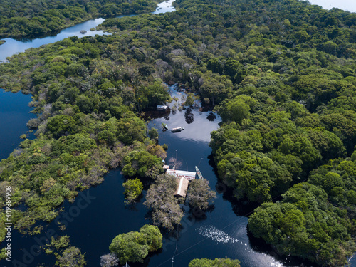 Drone aerial view of forest trees  small houses and boats in the biggest flood of the Negro river history in the Amazon rainforest. Concept of environment  ecology  climate change  global warming.