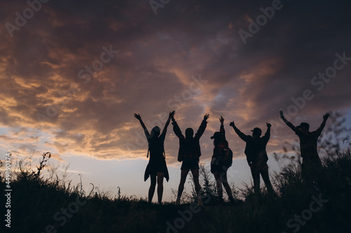 Silhouettes of people, young man and women meeting sunset outdoors, in summer forest, meadow. Active lifestyle, friendship, care, ecology concept