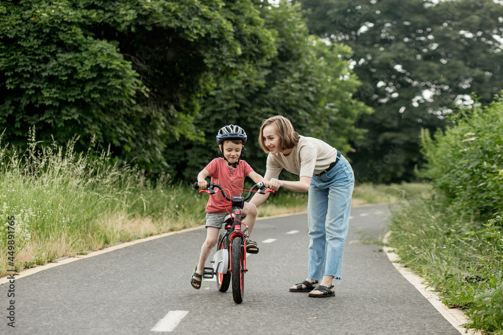 Happy Mother teaches child son to ride a bike on the bike path Happy Mother teaches child son to ride a bike on the bike path