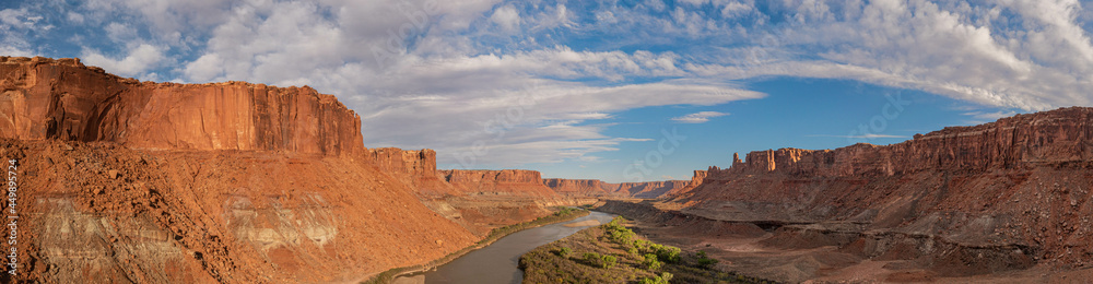 Aerial panorama in of Canyonlands National Park looking south over the Green River into the orange canyons with partly cloudy skies and evening light.