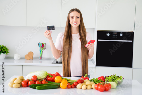 Photo portrait young woman cooking keeping credit card smartphone waiting delivery