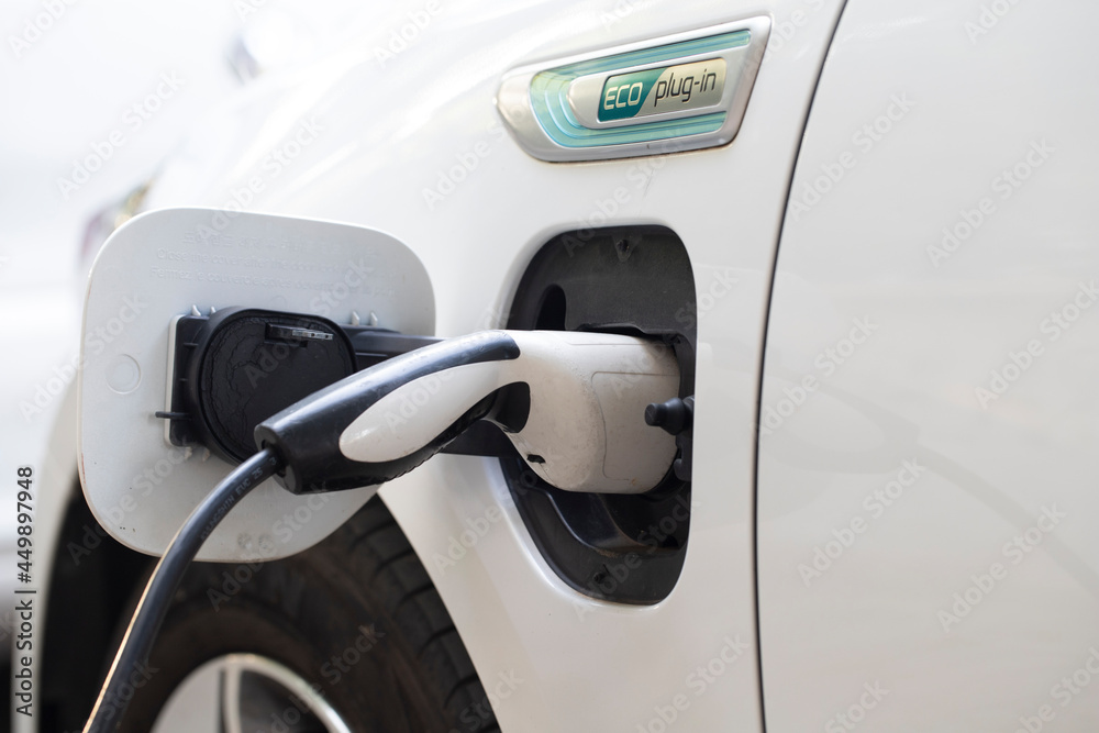 Power supply for electric car charging. Electric car charging station. Close up of the power supply plugged into an electric car being charged. car plugin hybrid. Power supply for electric car charging. Electric car charging station. Close up of the power supply plugged into an electric car being charged. car plugin hybrid.