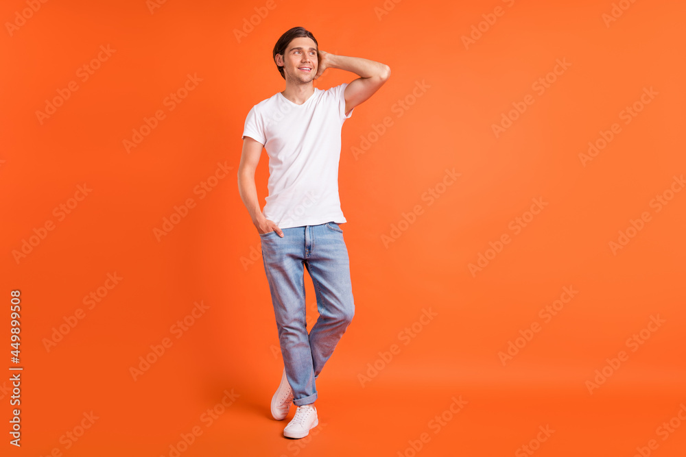 Full body photo of cheerful young happy positive man look empty space imagine isolated on orange color background Full body photo of cheerful young happy positive man look empty space imagine isolated on orange color background