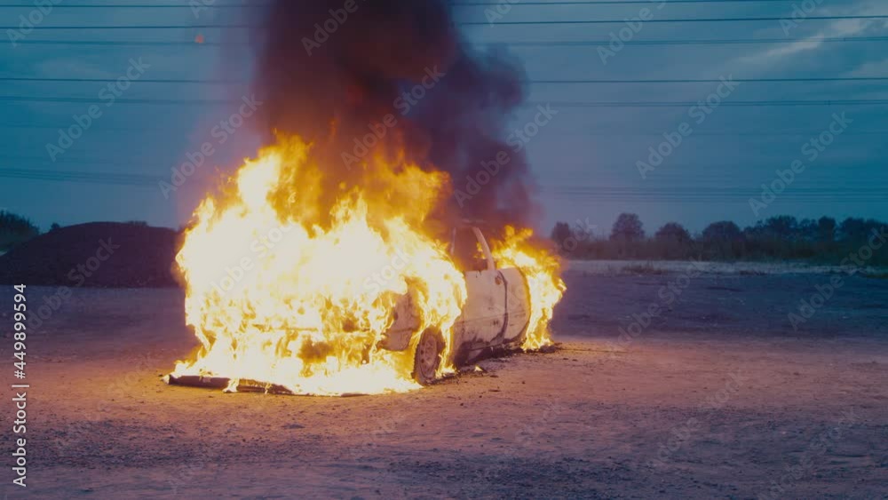 A passenger car on the street is engulfed in flames and completely burns to ashes.