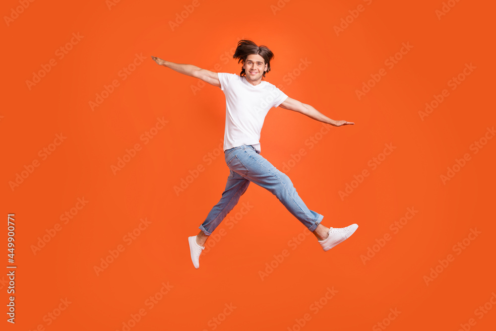 Fototapeta premium Full body photo of cheerful young happy positive man jump up hands plane wings isolated on orange color background