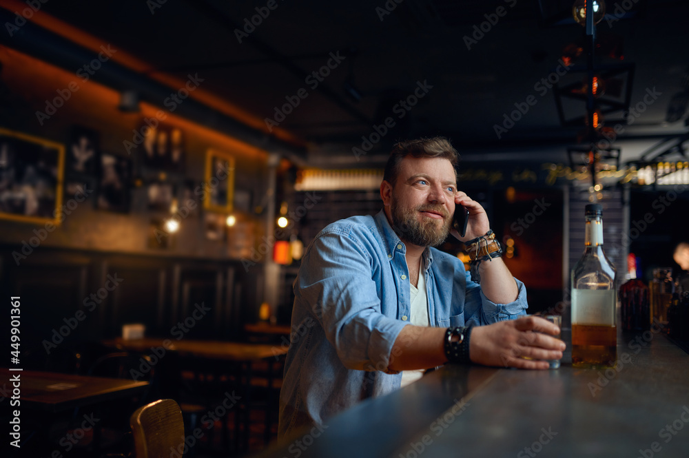 Man talking by mobile phone at the counter in bar