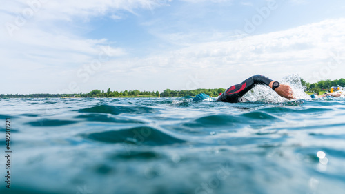 Obraz na plátně Triathlete in a wetsuit swims in a lake at a triathlon competition