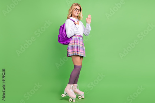 Full length body size view of attractive cheerful girl riding quad waving greetings isolated over green color background