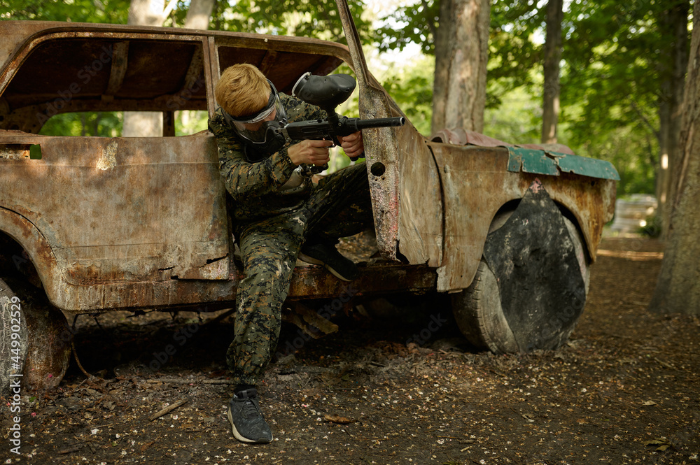 Paintball player in uniform and mask in forest