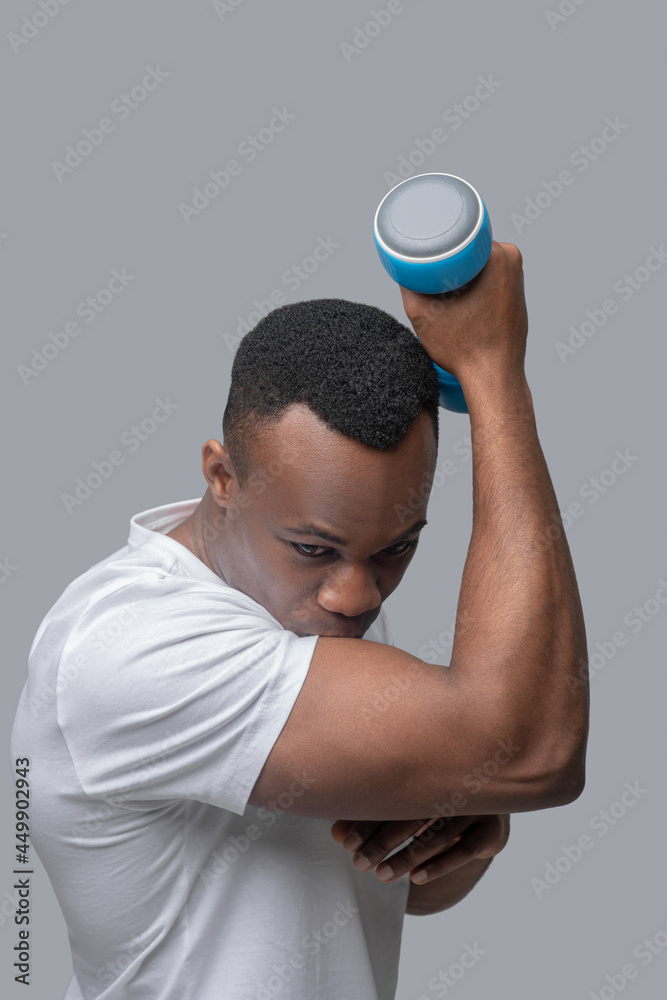 A dark-skinned young guy exercising with dumbbells