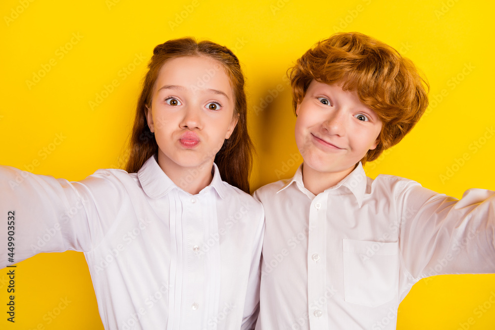 Portrait of two funky good mood best friends pupils take selfie go back to school isolated on yellow color background Portrait of two funky good mood best friends pupils take selfie go back to school isolated on yellow color background