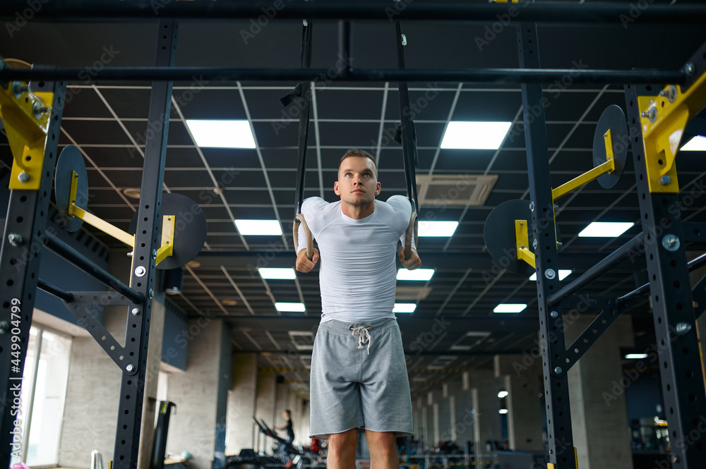 Muscular man doing abs exercise on the rings