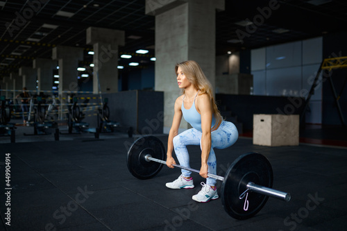 Sexy woman doing exercise with barbell in gym