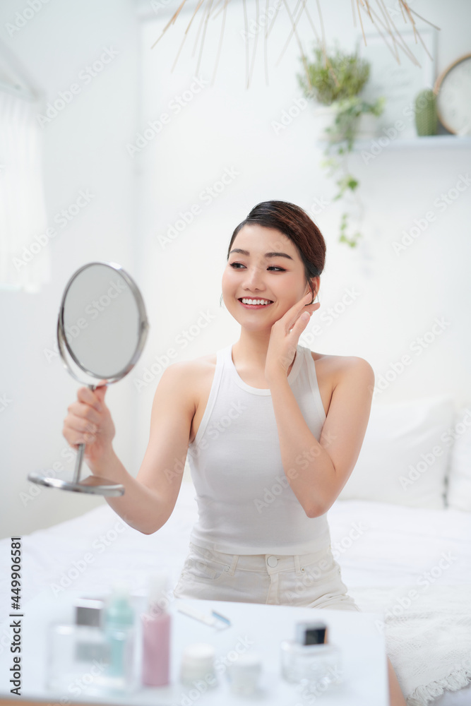 Pretty woman holding a mirror and smiling into the camera