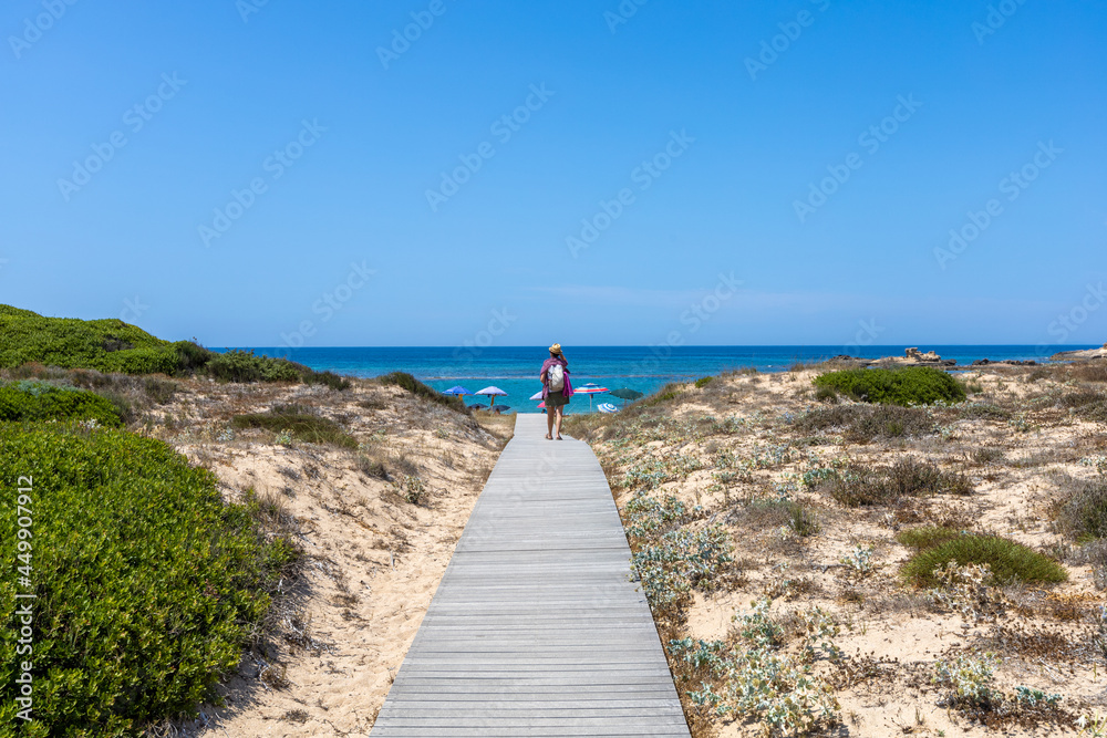 Woman walks on sand dune in Sa Mesa Longa beach. Capo Mannu, San Vero Milis, Oristano, Sardinia, Italy, Europe