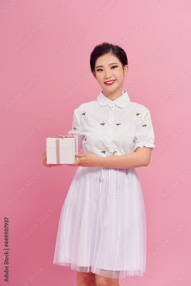 Picture of happy asian girl child standing isolated over pink background. Looking camera holding gift box surprise. Picture of happy asian girl child standing isolated over pink background. Looking camera holding gift box surprise.