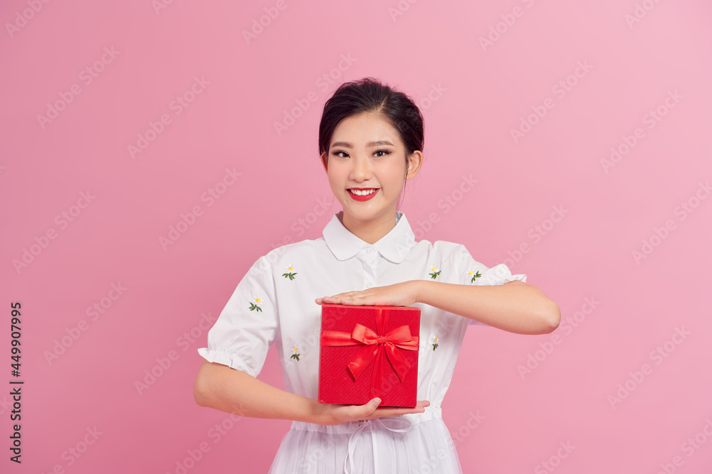 Cheerful attractive young woman holding gift boxes over pink background Cheerful attractive young woman holding gift boxes over pink background