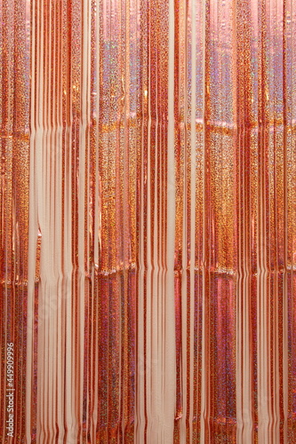 Shiny golden tinsel lines on the wall, vertical texture for a festive background