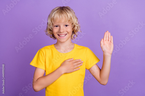 Photo of positive happy charming boy hold hand chest give oath pledge honest isolated on violet color background