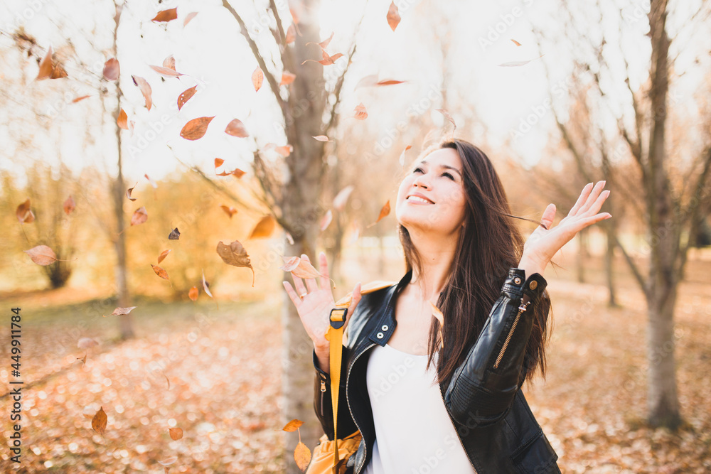 Happy woman in the park greets autumn with bright yellow leaves - cheerful euphoria Happy woman in the park greets autumn with bright yellow leaves - cheerful euphoria